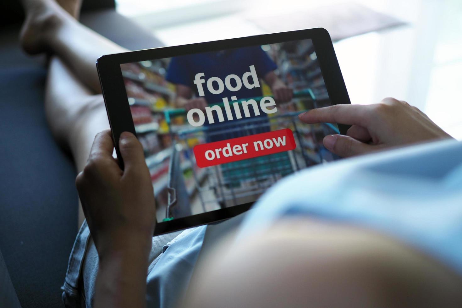 Women use tablets to order food online while lying on the couch at home. photo