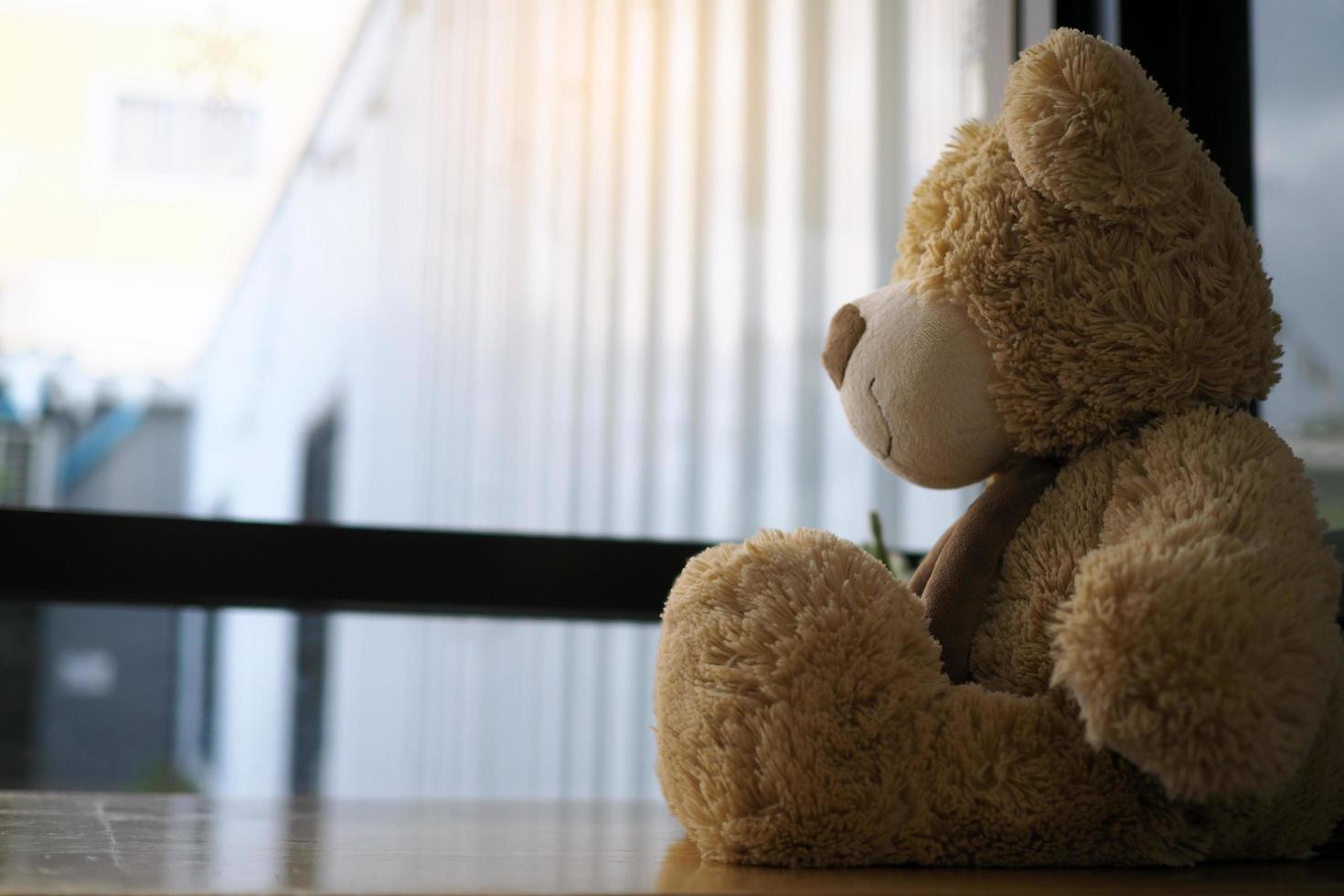 Child concept of sorrow. Teddy bear sitting leaning against the wall of the house alone, look sad and disappointed. photo