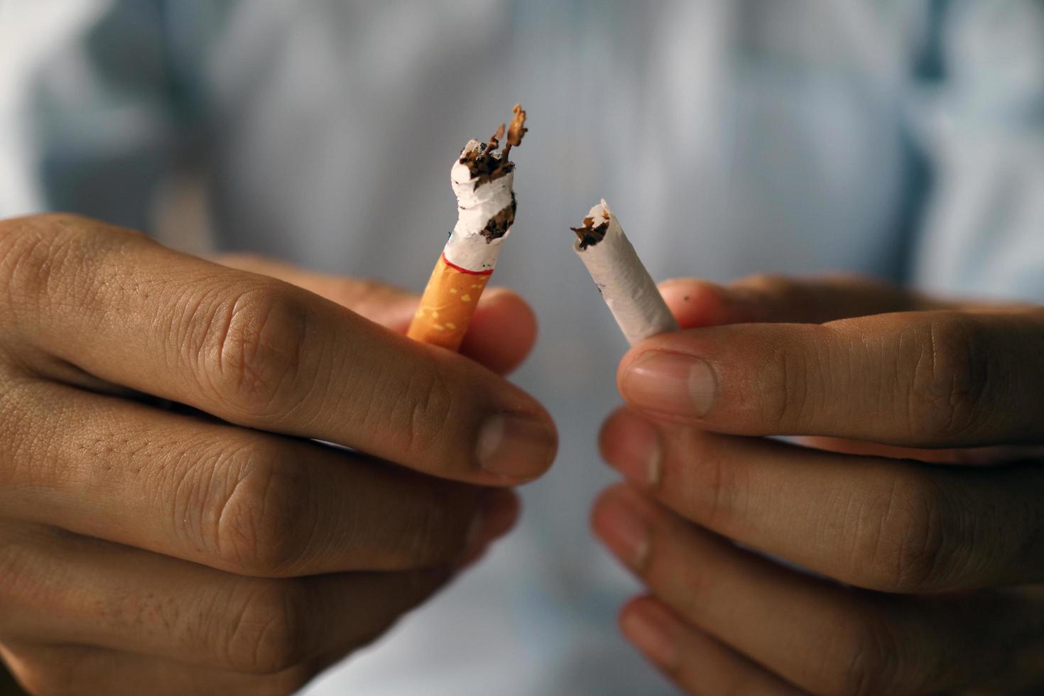 mano rompiendo cigarrillos el concepto de fumar causa cáncer de pulmón. solo di no foto