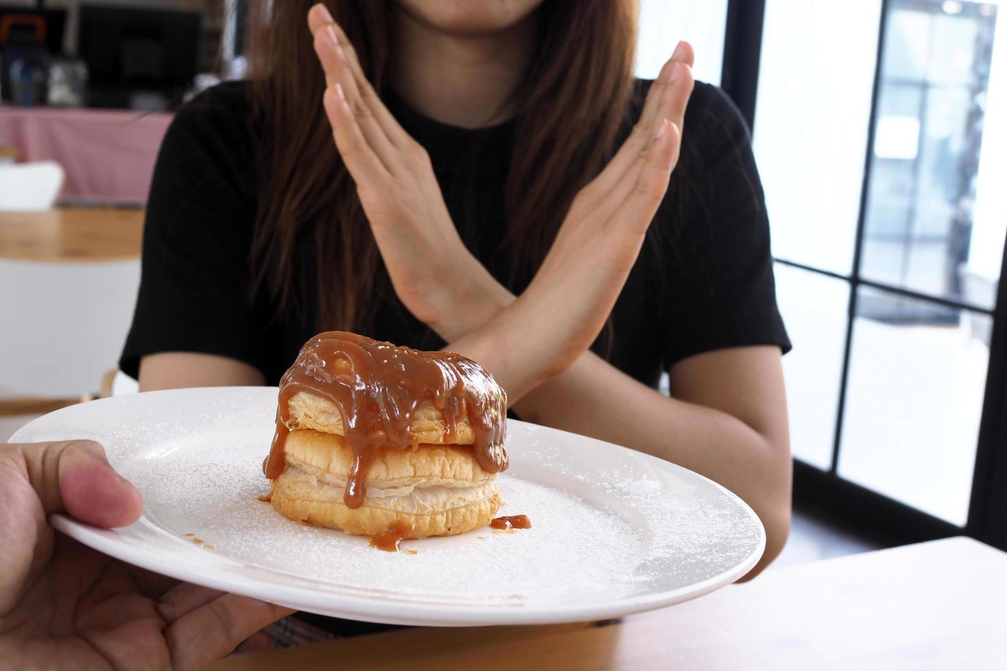 Young women refuse to eat sweet desserts for weight loss goals. diet concept photo