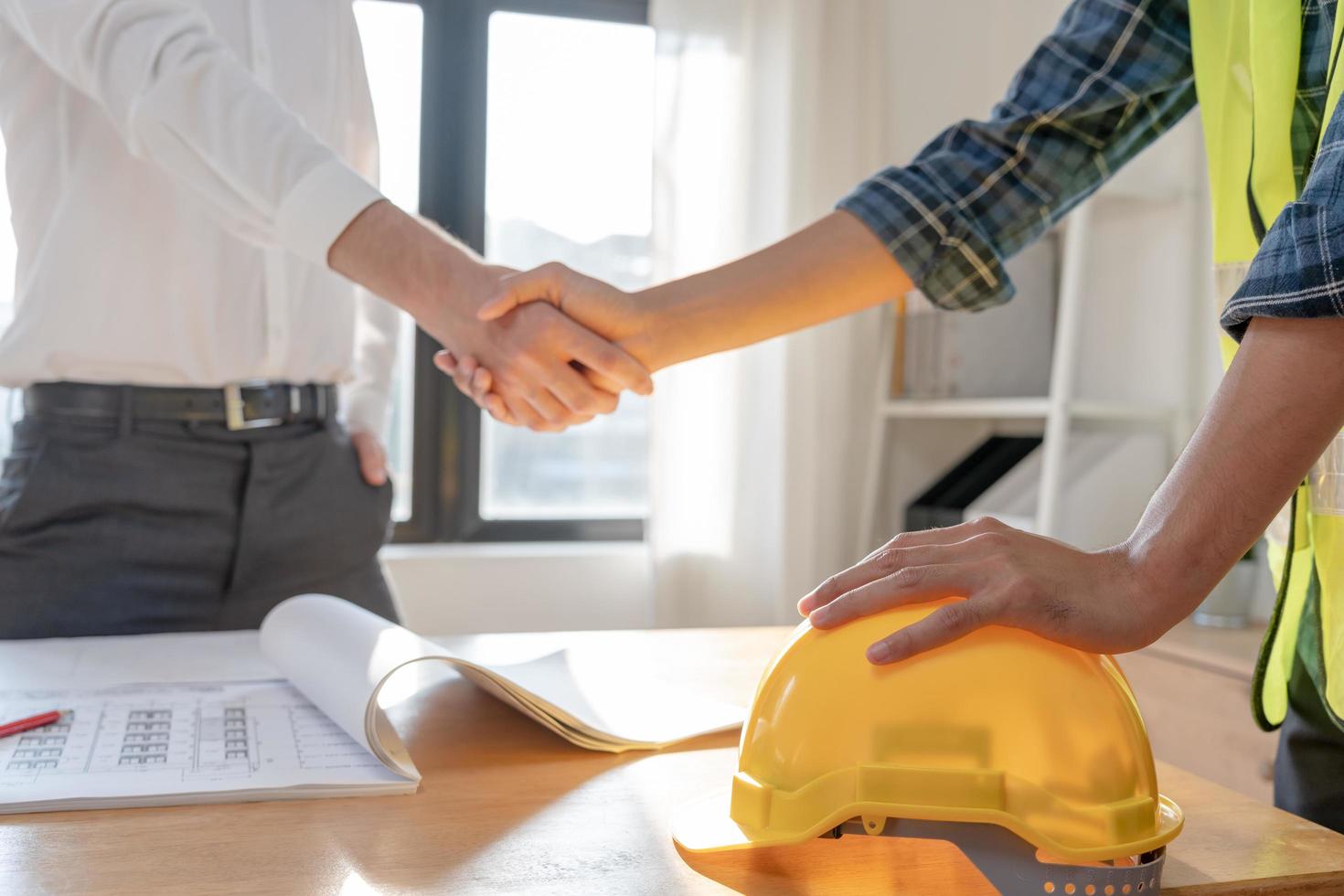 manos del equipo de trabajadores de la construcción agitando el plan de inicio de saludo nuevo contrato de proyecto en el centro de oficinas en el sitio de construcción, industria, arquitectura, socio, trabajo en equipo, acuerdo, propiedad, contactos. foto