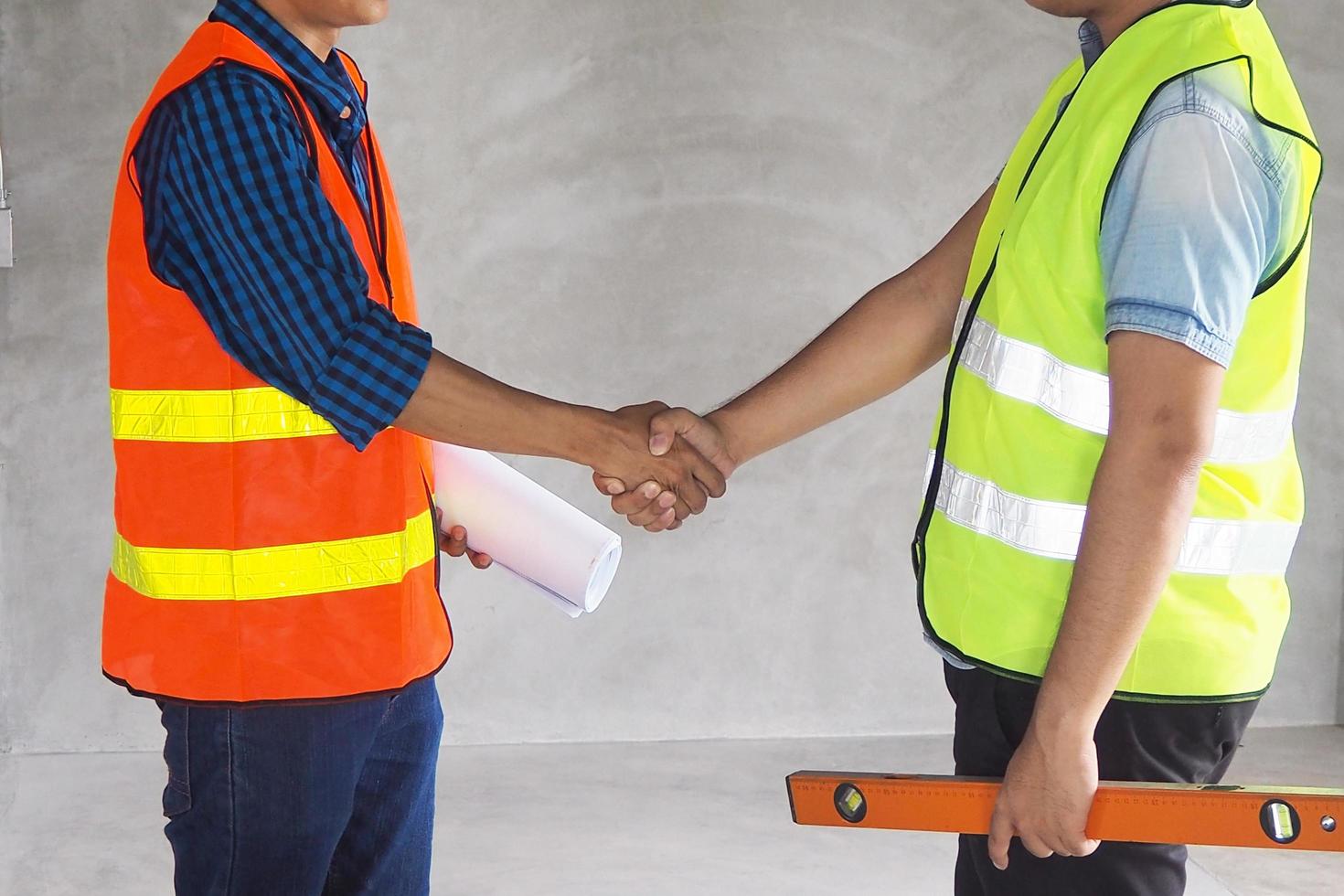 Construction worker wearing a vest is holding hands while working on a building under construction. photo