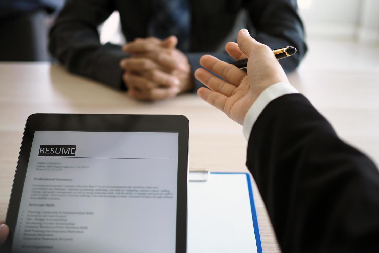 Executives are interviewing and watching the resume via tablet. Focus on resume writing tips, applicant qualifications, interview skills and preparation before the interview. photo