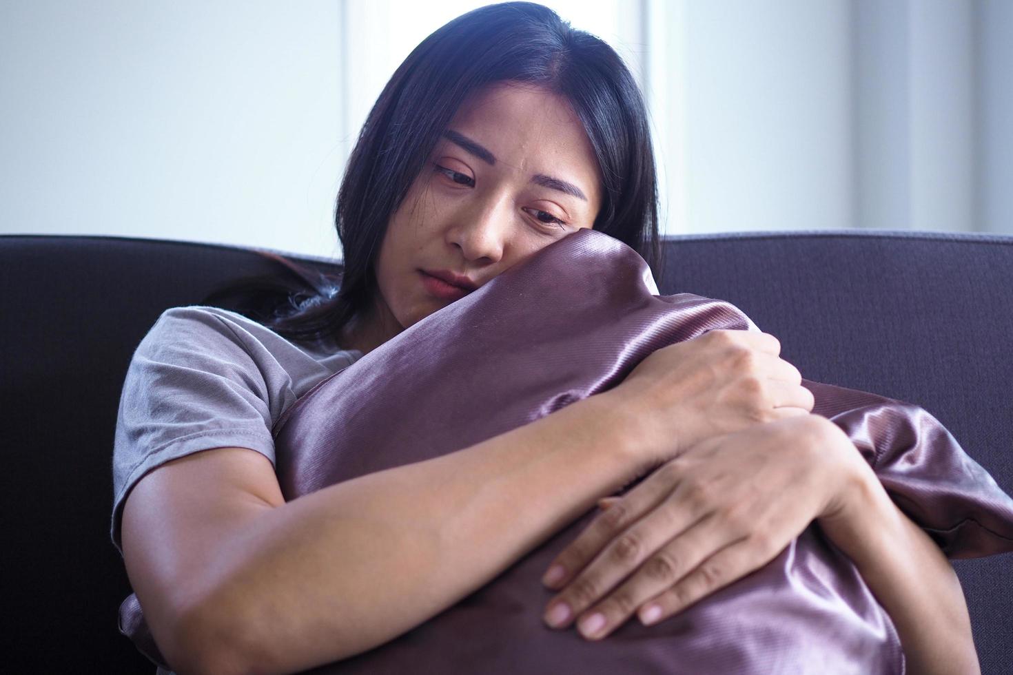 The woman sat and hugged the pillow on the sofa in the house. The expression and despondency and despair. photo