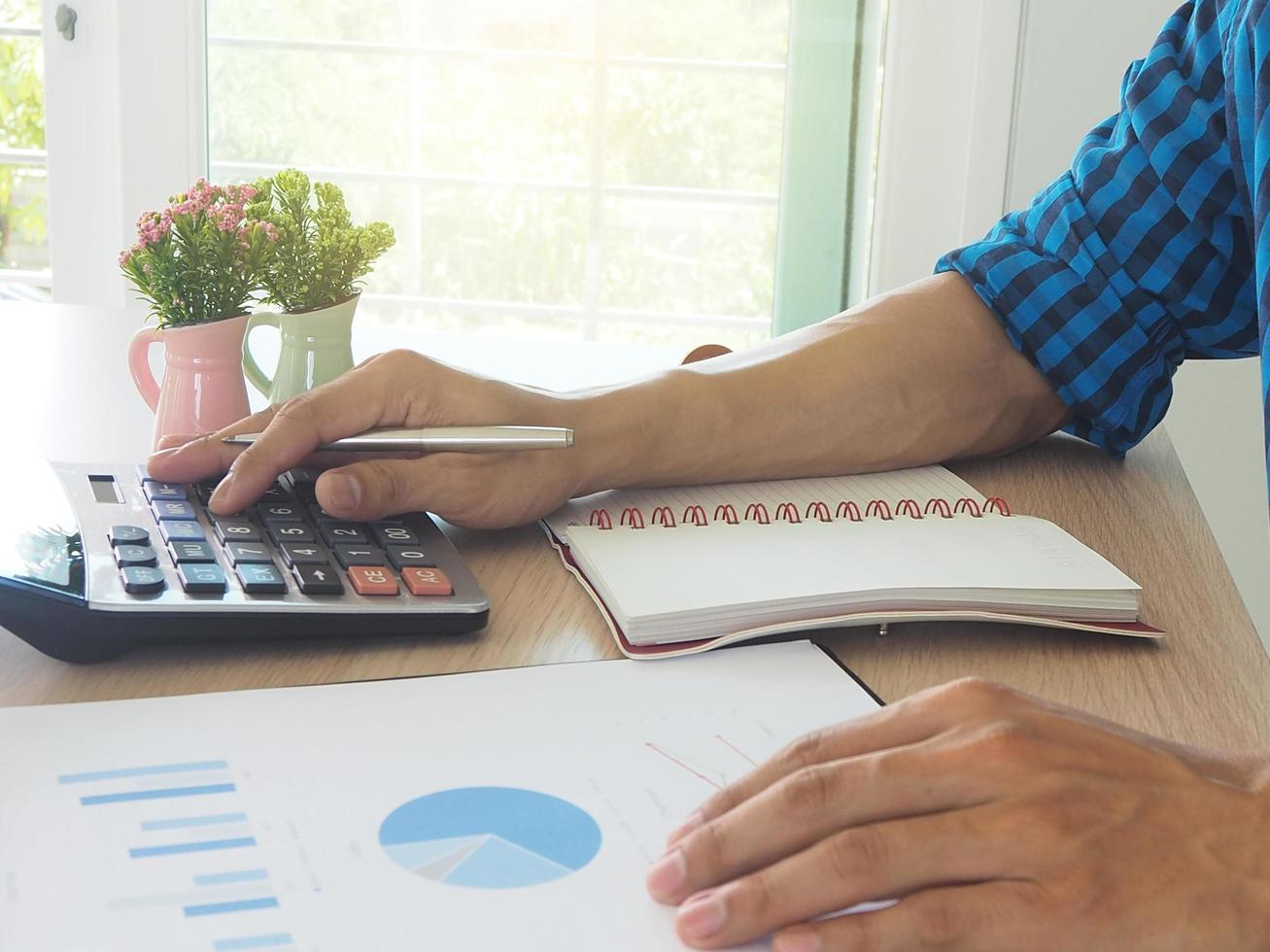 Accounting concept Men's hand uses a calculator to calculate statistics. About his work Calculate the data in the job. photo