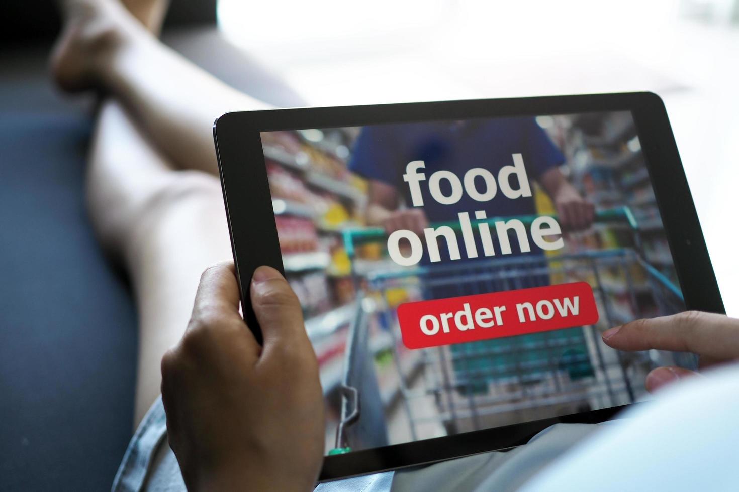 Women use tablets to order food online while lying on the couch at home. photo