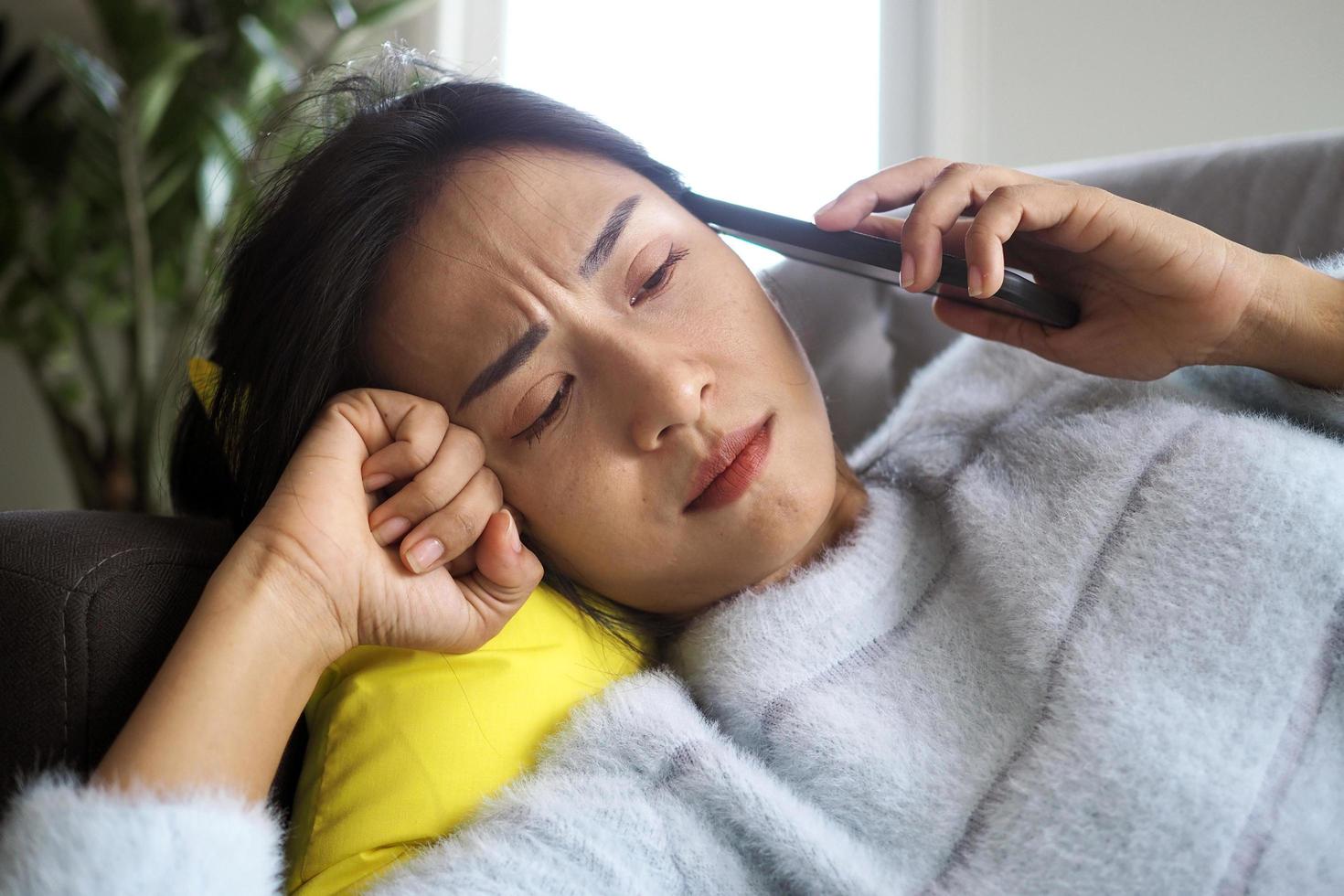 The sick woman lying on the couch had anxious facial expression, disappointment and sad after receiving bad news on the phone. photo