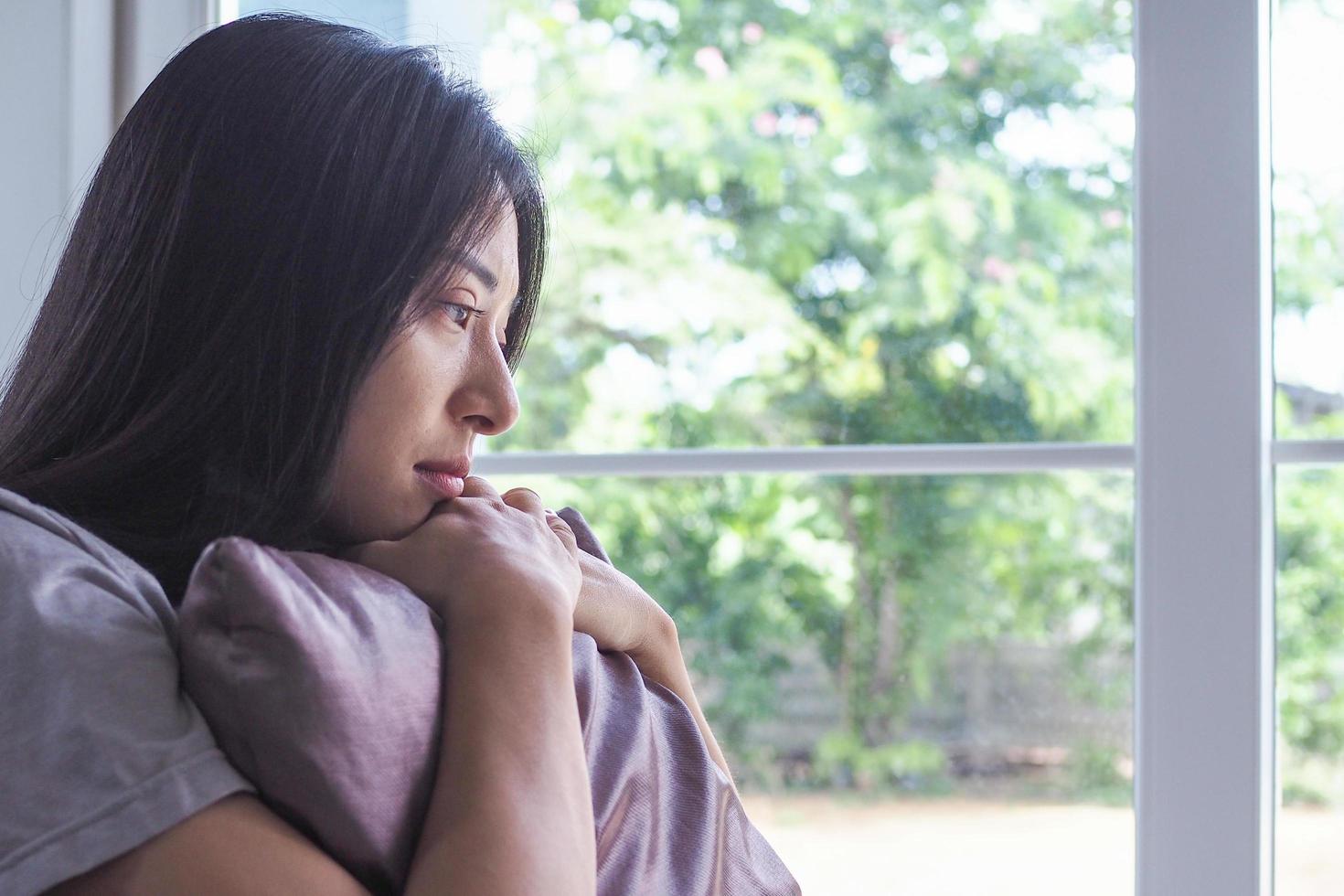 The woman is hugging the pillow on the sofa inside the house. In a sad, depressing manner, thinking hard about the problem. photo