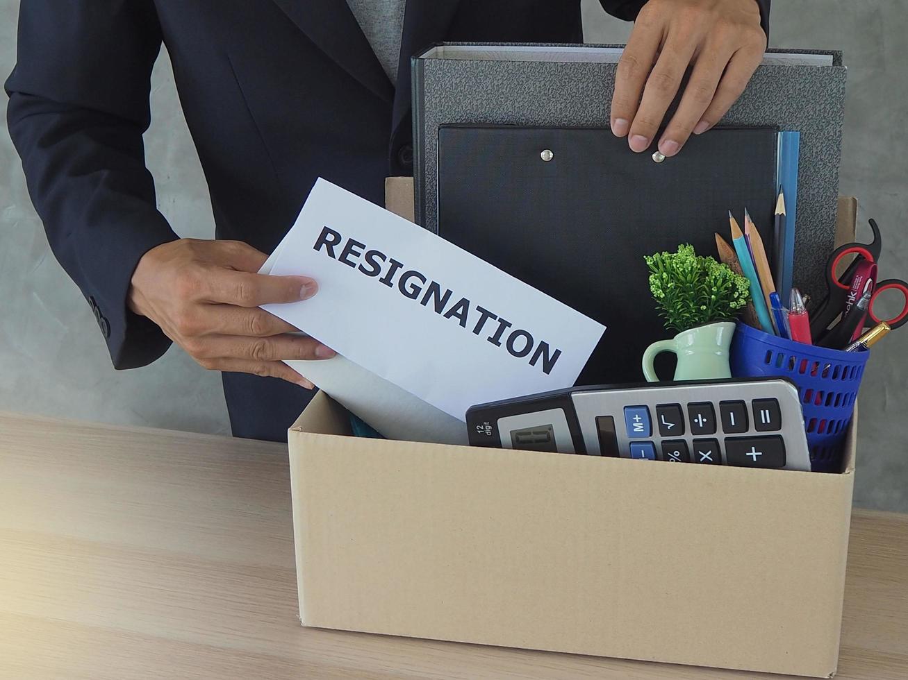 Business men are storing personal belongings in a brown paper box. And a letter of resignation photo