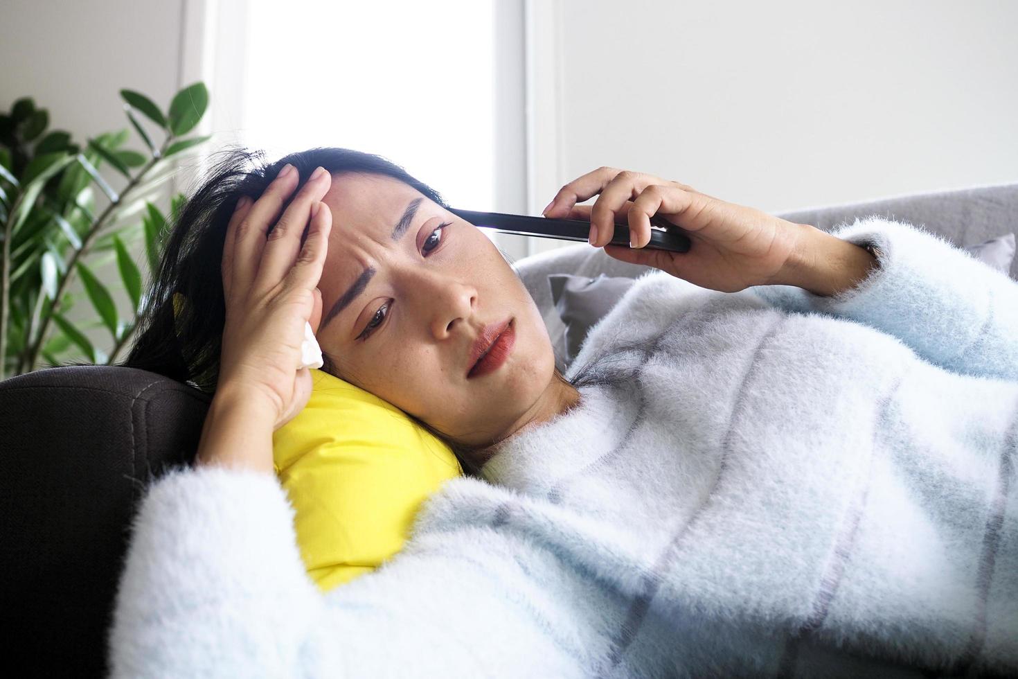 The sick woman lying on the couch had anxious facial expression, disappointment and sad after receiving bad news on the phone. photo