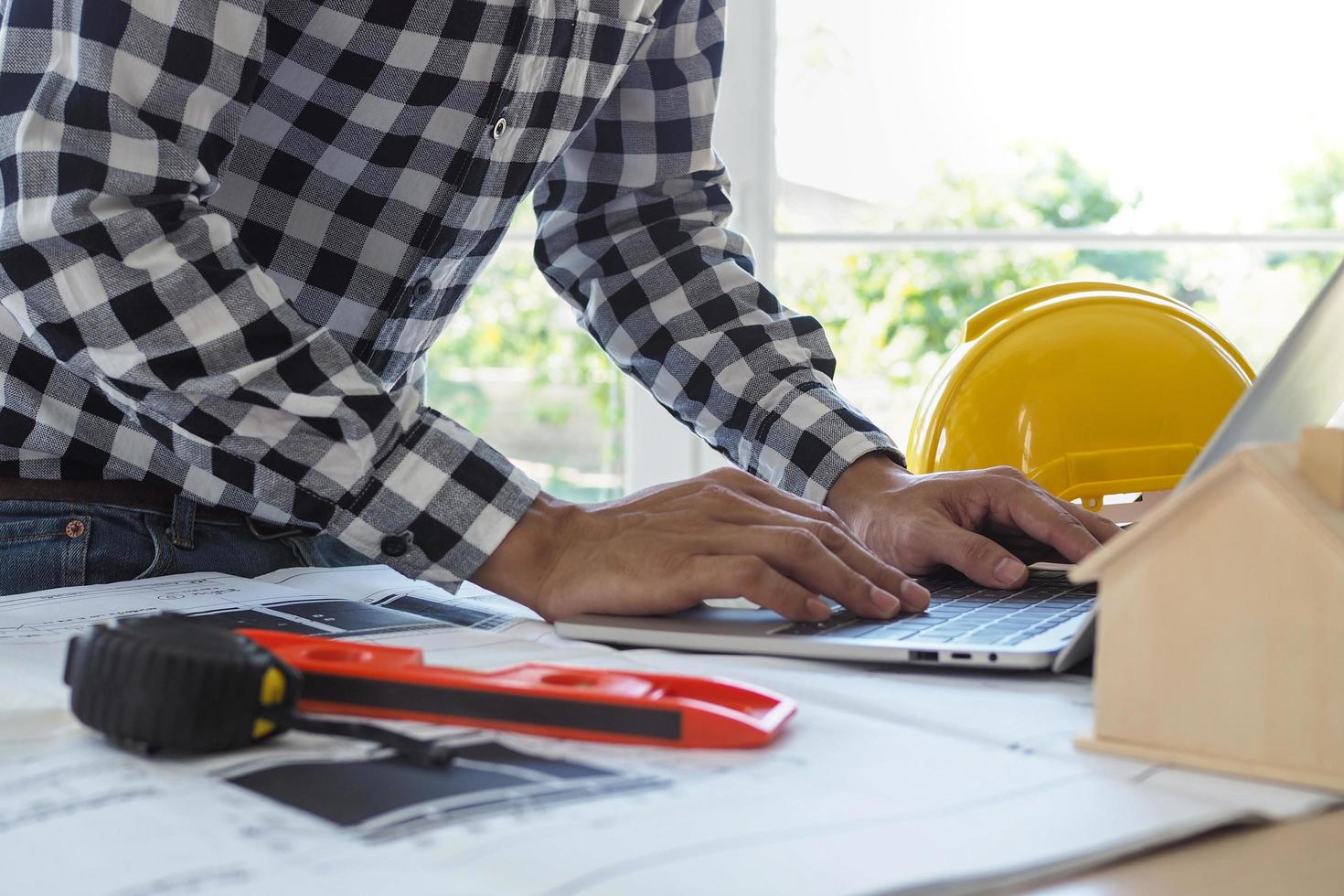 los ingenieros trabajan con computadoras portátiles y planos. calcular y comprobar el proyecto de construcción foto