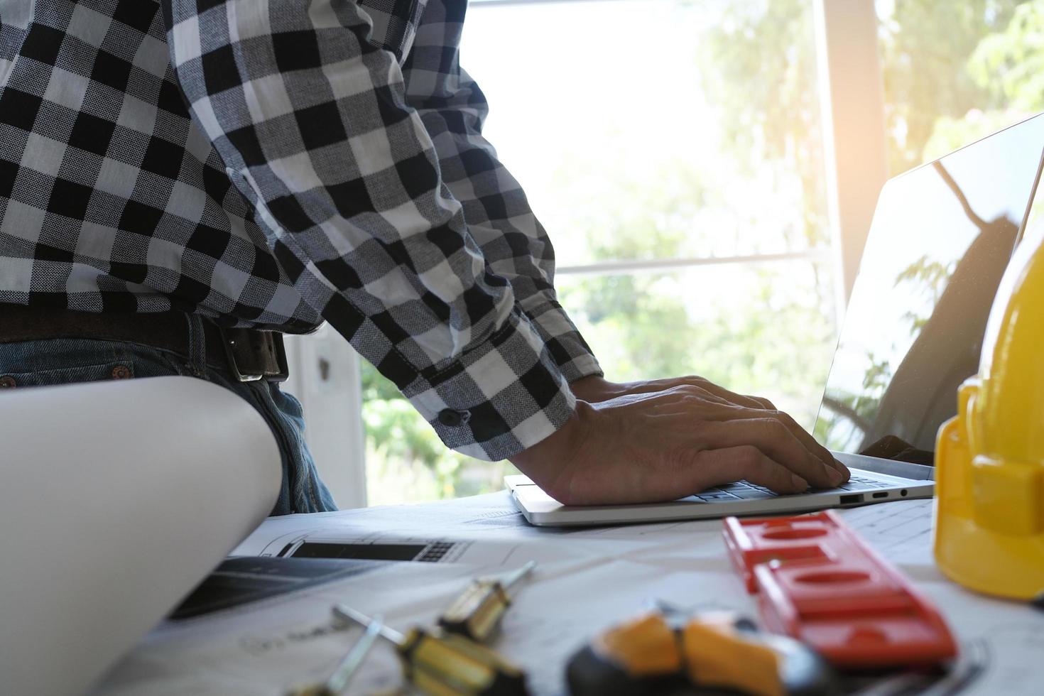 los ingenieros usan computadoras portátiles y revisan el plano. preparar la planificación del proyecto de construcción foto