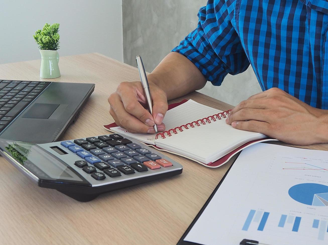 Man hand is writing a calculations record with a statistical graph. photo