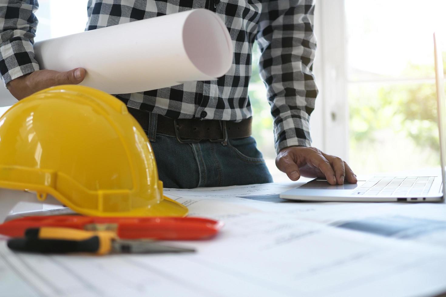 los ingenieros trabajan con computadoras portátiles y planos. calcular y comprobar el proyecto de construcción foto