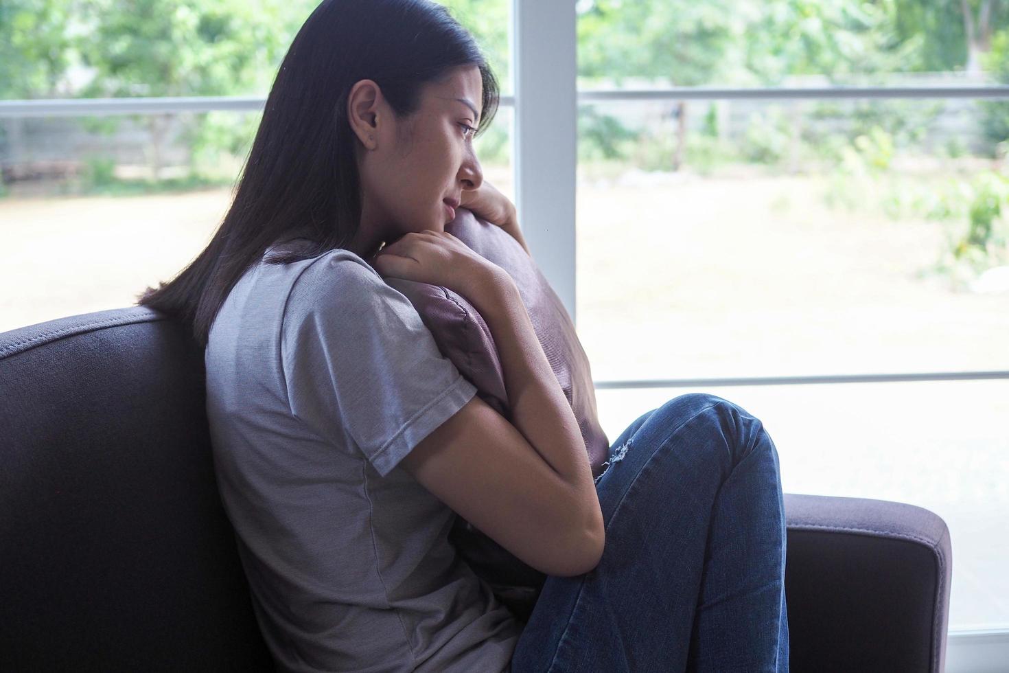 The woman sat and hugged the pillow on the sofa in the house. The expression and despondency and despair. photo