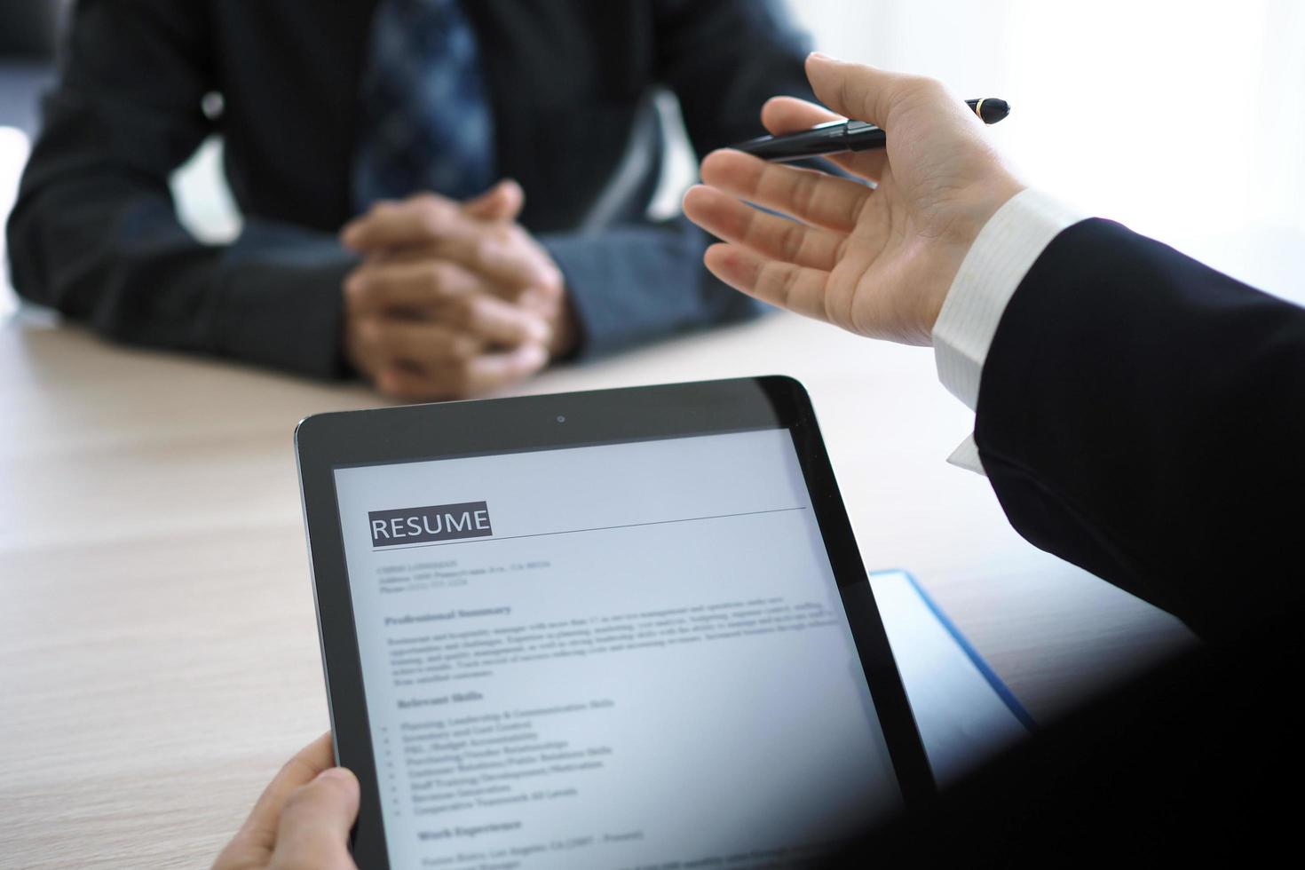 Executives are interviewing candidates and holding a tablet, opening the resume from the email that the applicant submits online. Discussing attitudes about work and special abilities. Considerations photo