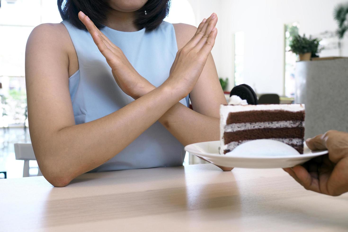 Young women refuse to eat chocolate cakes for weight loss goals. diet concept photo