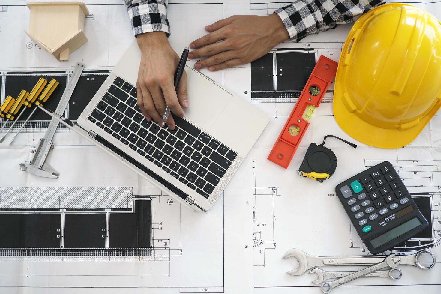 los ingenieros trabajan con computadoras portátiles y planos. calcular y comprobar el proyecto de construcción. foto