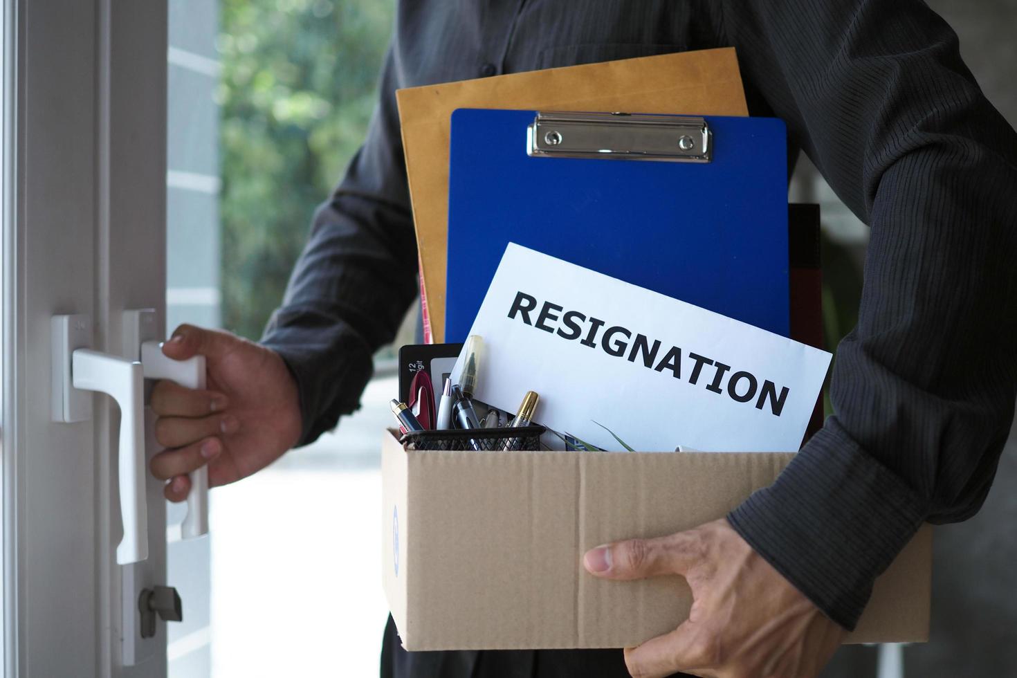 Businessmen hold boxes for personal belongings and resignation letters and open doors from the office. Including resignation from job positions and vacancies photo