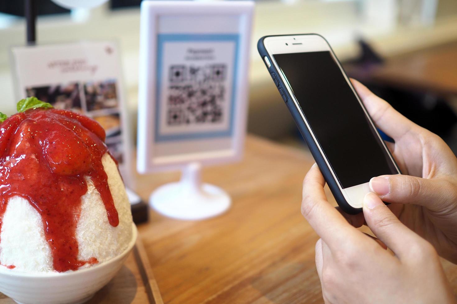 Hands use the phone to scan the QR code to receive discounts from Binsu orders in the cafe. photo