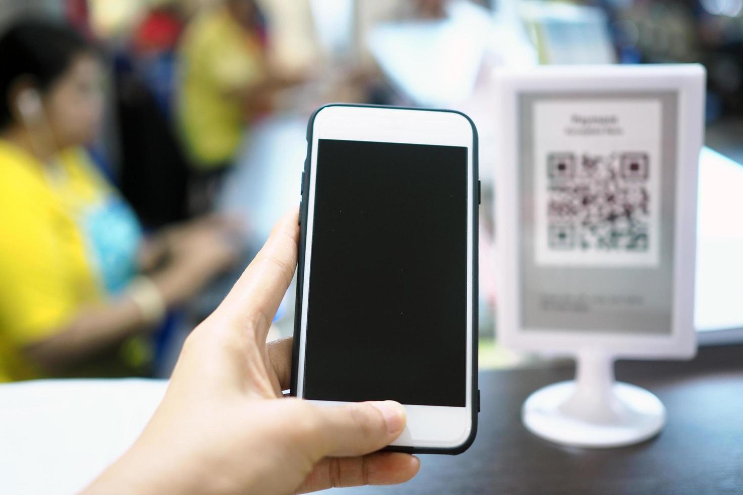 Hands use the phone to scan the QR code to accumulate points before paying at the counter. photo