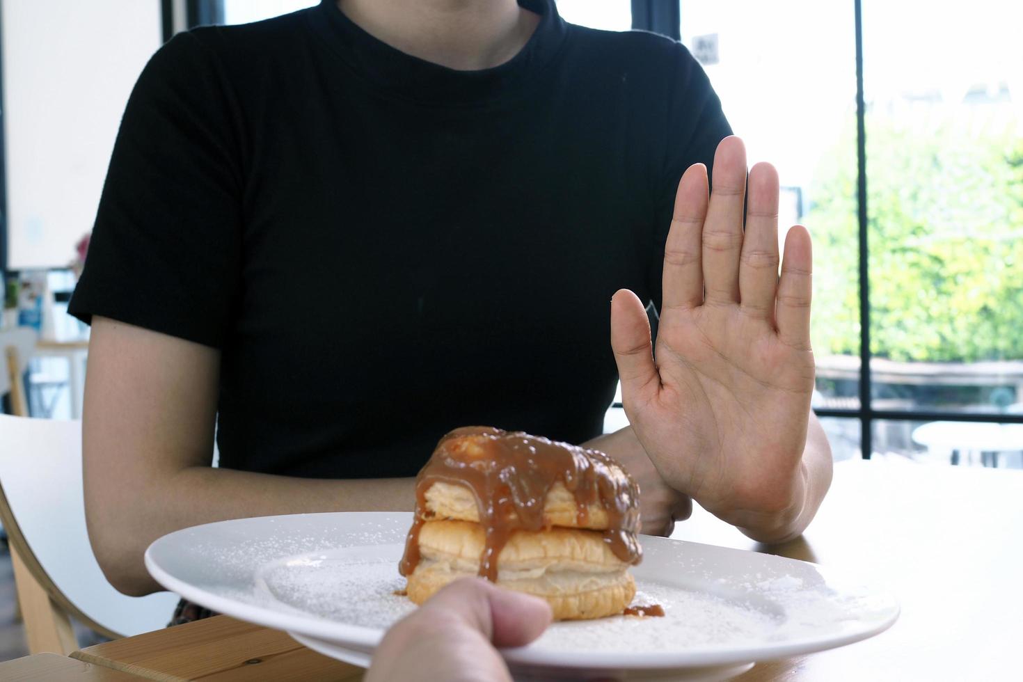 las mujeres de atención médica usan las manos para empujar postres dulces. negarse a comer harina y azúcar. concepto de dieta foto