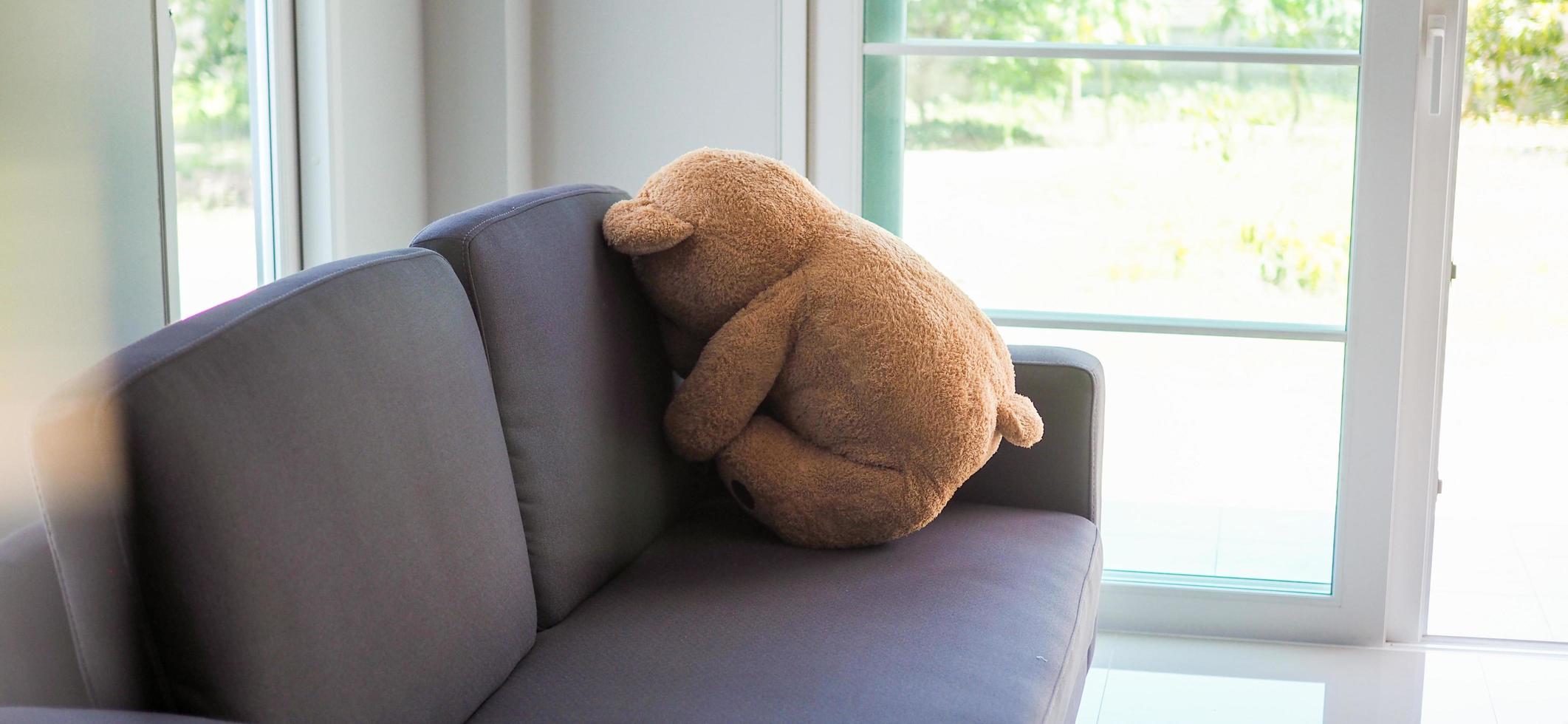 Child concept of sorrow. Teddy bear sitting leaning against the wall of the house alone, look sad and disappointed. photo