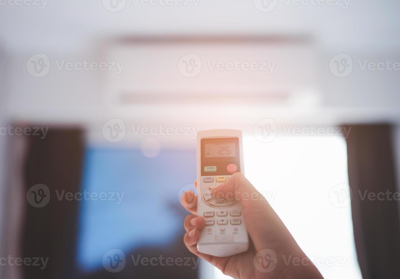 Air conditioner inside the room with hand operating remote controller. photo