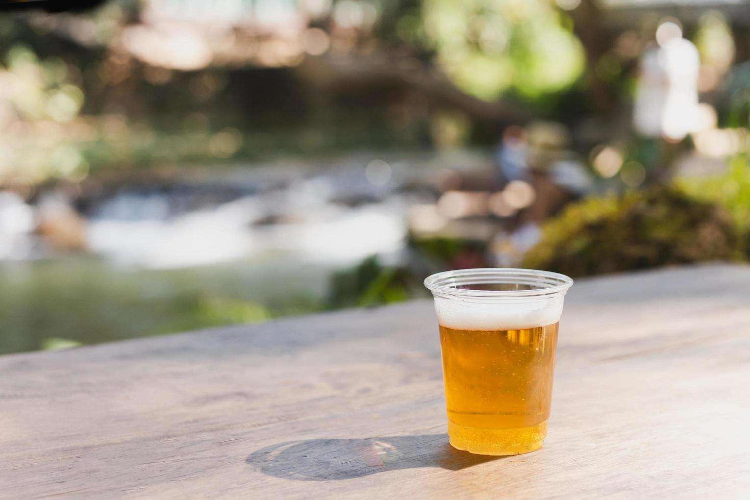 aislado de cerveza en vaso de plástico sobre mesa de madera. foto