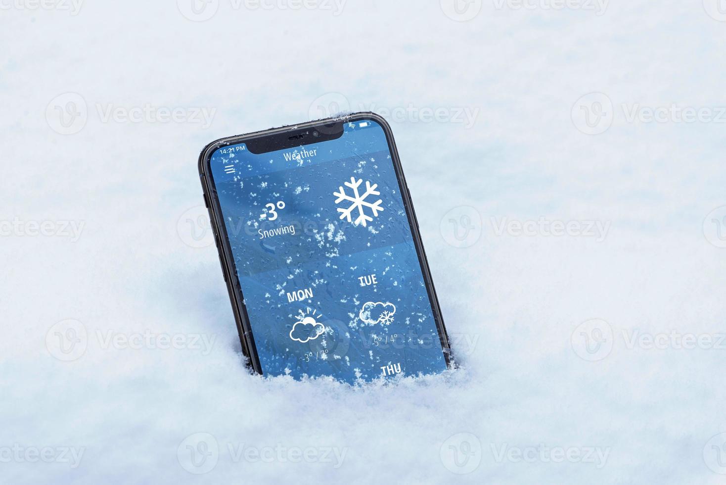 Phone with the current temperature in Celsius and with the weather forecast for the coming days. Modern app interface. The phone sank into the snow photo