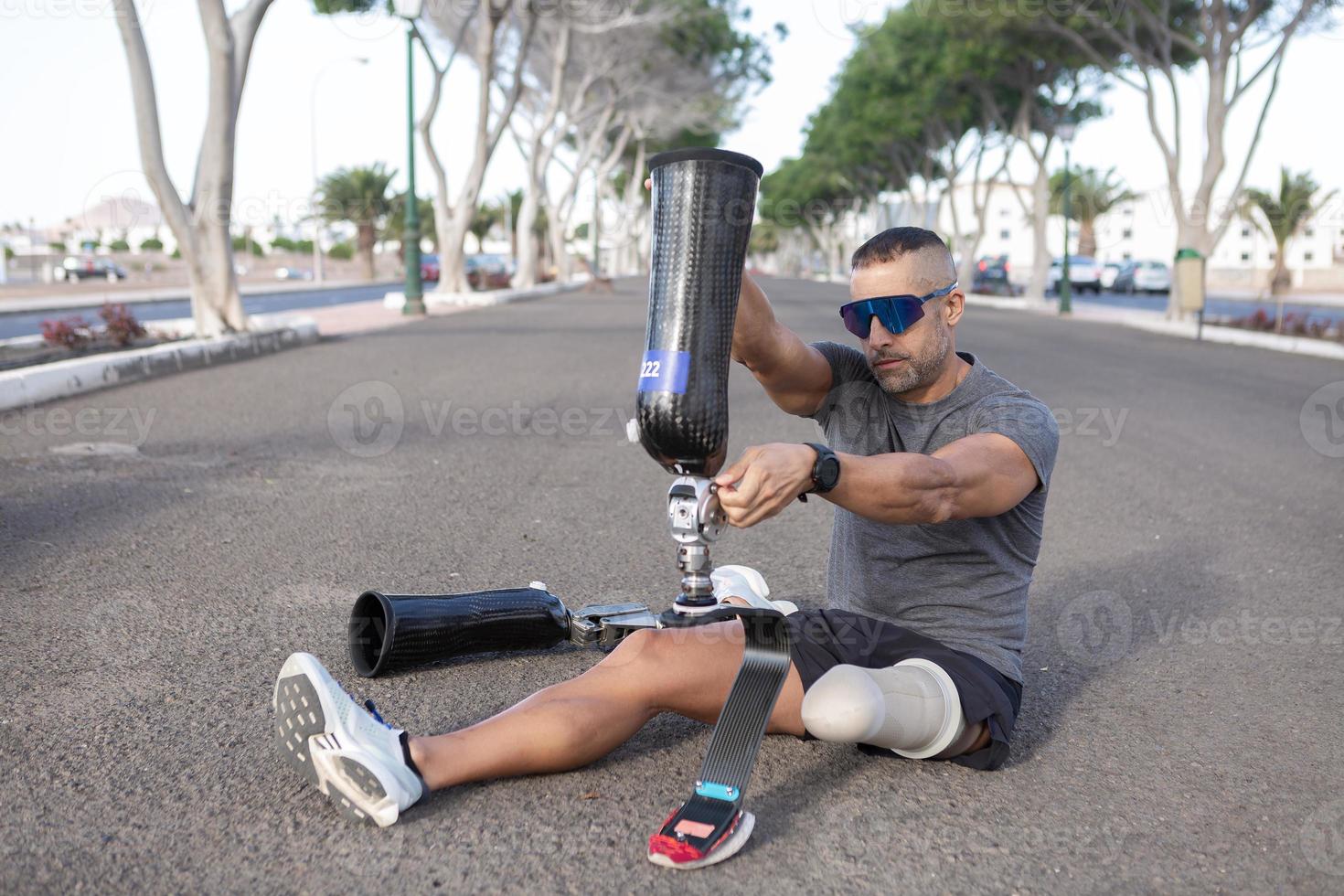 Male runner putting on leg prosthesis before running photo