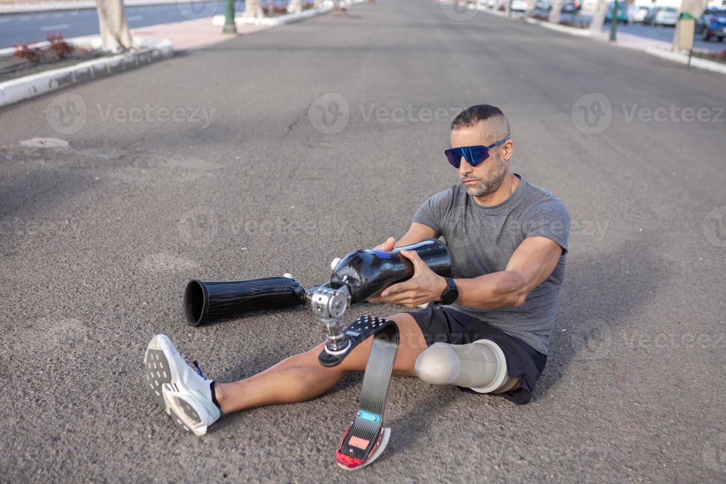 Male amputee putting on artificial leg before running outdoors photo