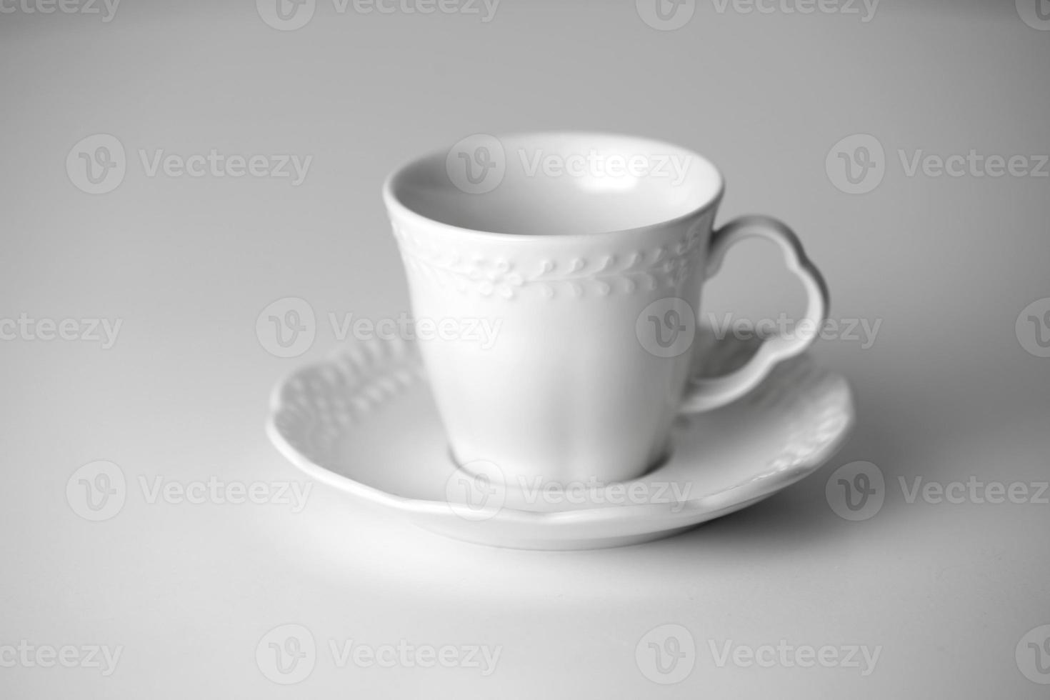 White tea cup and saucer with a pattern for drink on white background. Ceramic coffee cup or mug close up. Mockup classic porcelain utensils. copy space photo