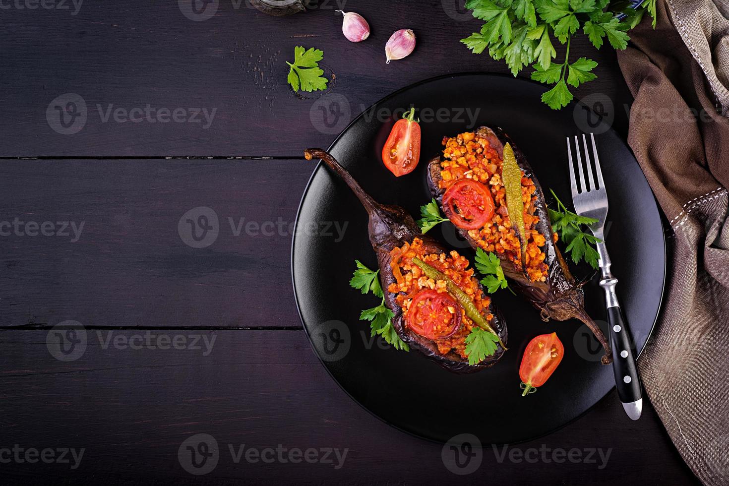 Karniyarik - turkish traditional aubergine eggplant meal. Stuffed eggplants with ground beef and vegetables baked with tomato sauce. Turkish cuisine. Top view. Copy space photo