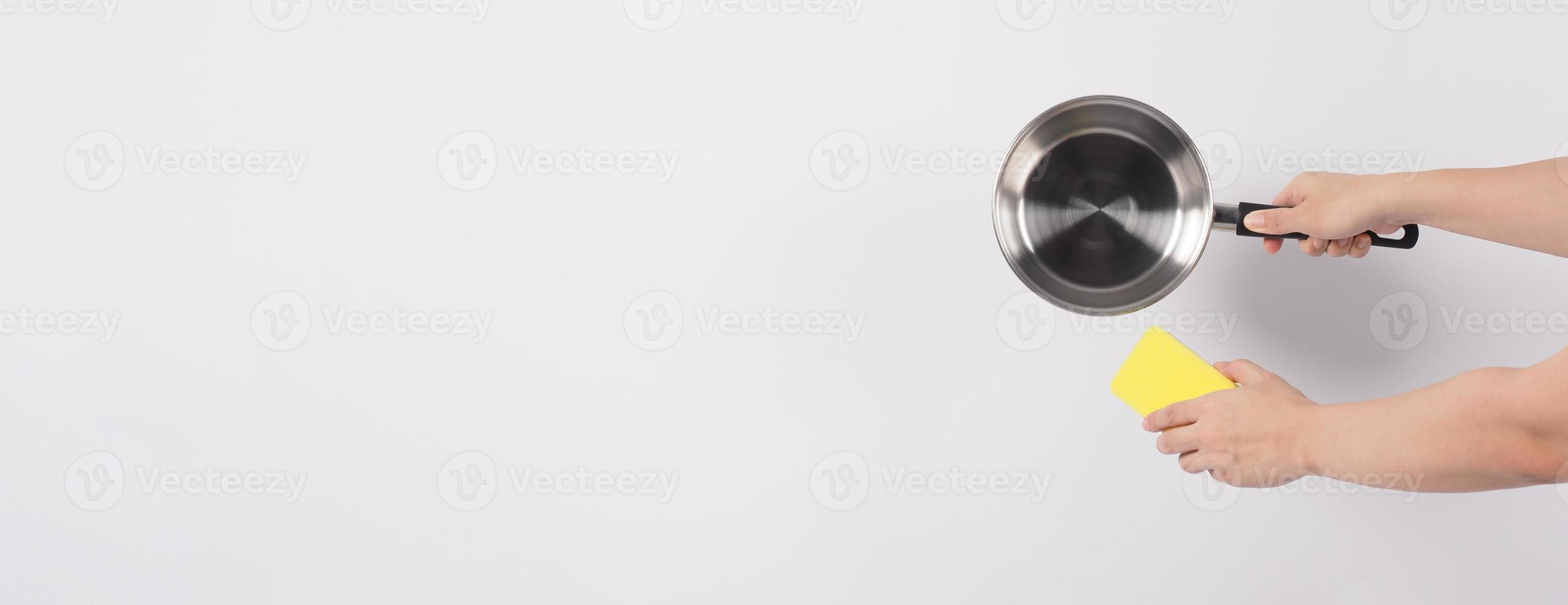Pot cleaning Man hand on white background cleaning the non stick pot with handy dish washing sponge which yellow color on the soft side and green on hard side for hygiene after cook. Electric pot photo