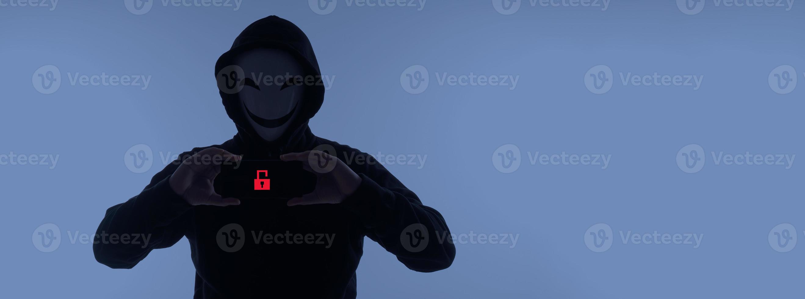 Hacker Anonymous and face mask with smartphone in hand. Man in black hood shirt holding and using mobile phone on white background. Represent cyber crime data hacking or stealing personal data concept photo