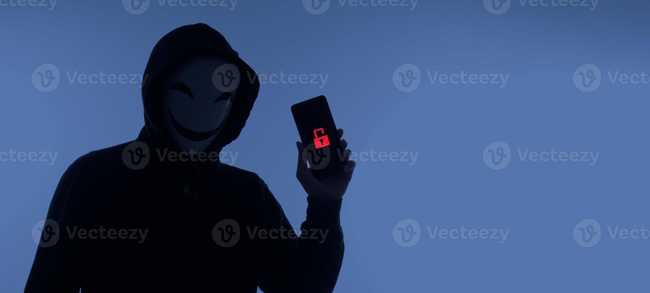 Hacker Anonymous and face mask with smartphone in hand. Man in black hood shirt holding and using mobile phone on white background. Represent cyber crime data hacking or stealing personal data concept photo