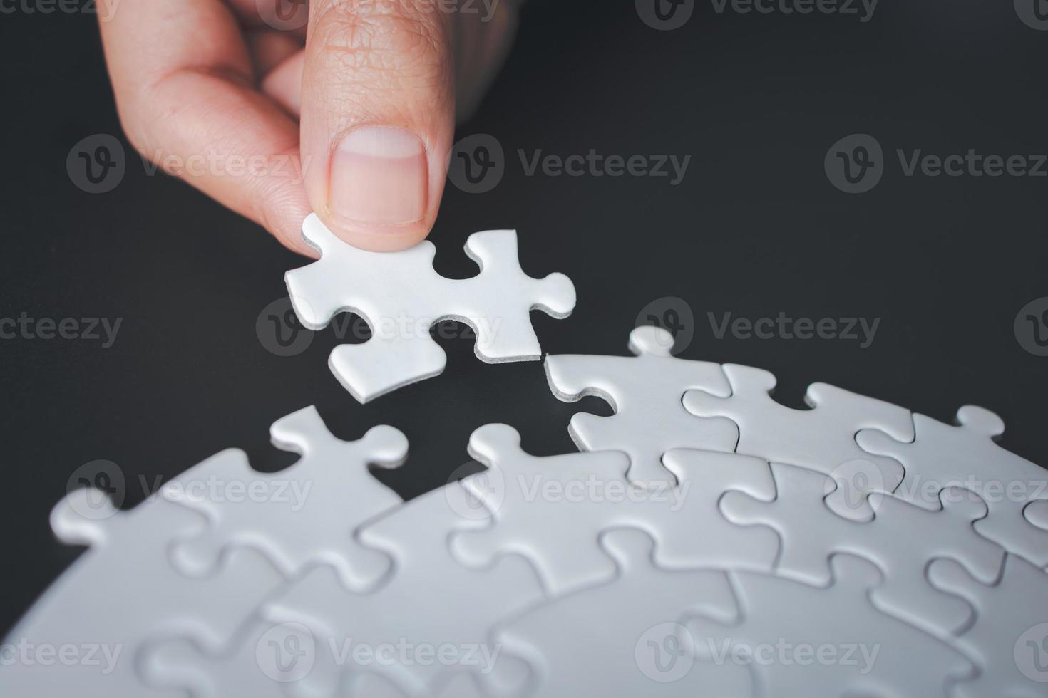 Hand put last piece of jigsaw puzzle. White unfinished jigsaw puzzle. The correct solution. Teamwork, Solving and completing the task. Assembling jigsaw puzzle pieces. photo