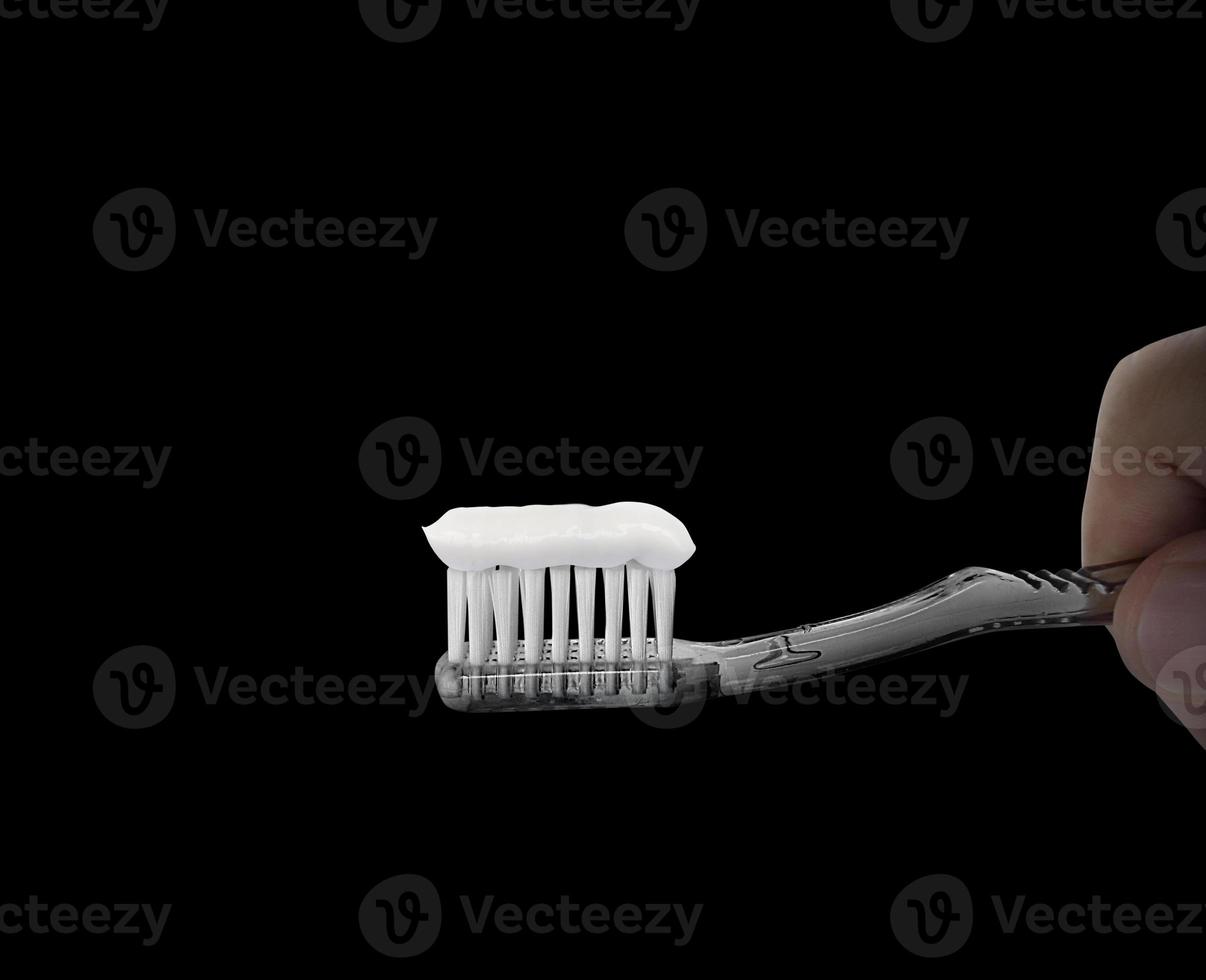mano sostenga el cepillo de dientes sobre fondo negro. concepto de símbolo de cuidado dental foto