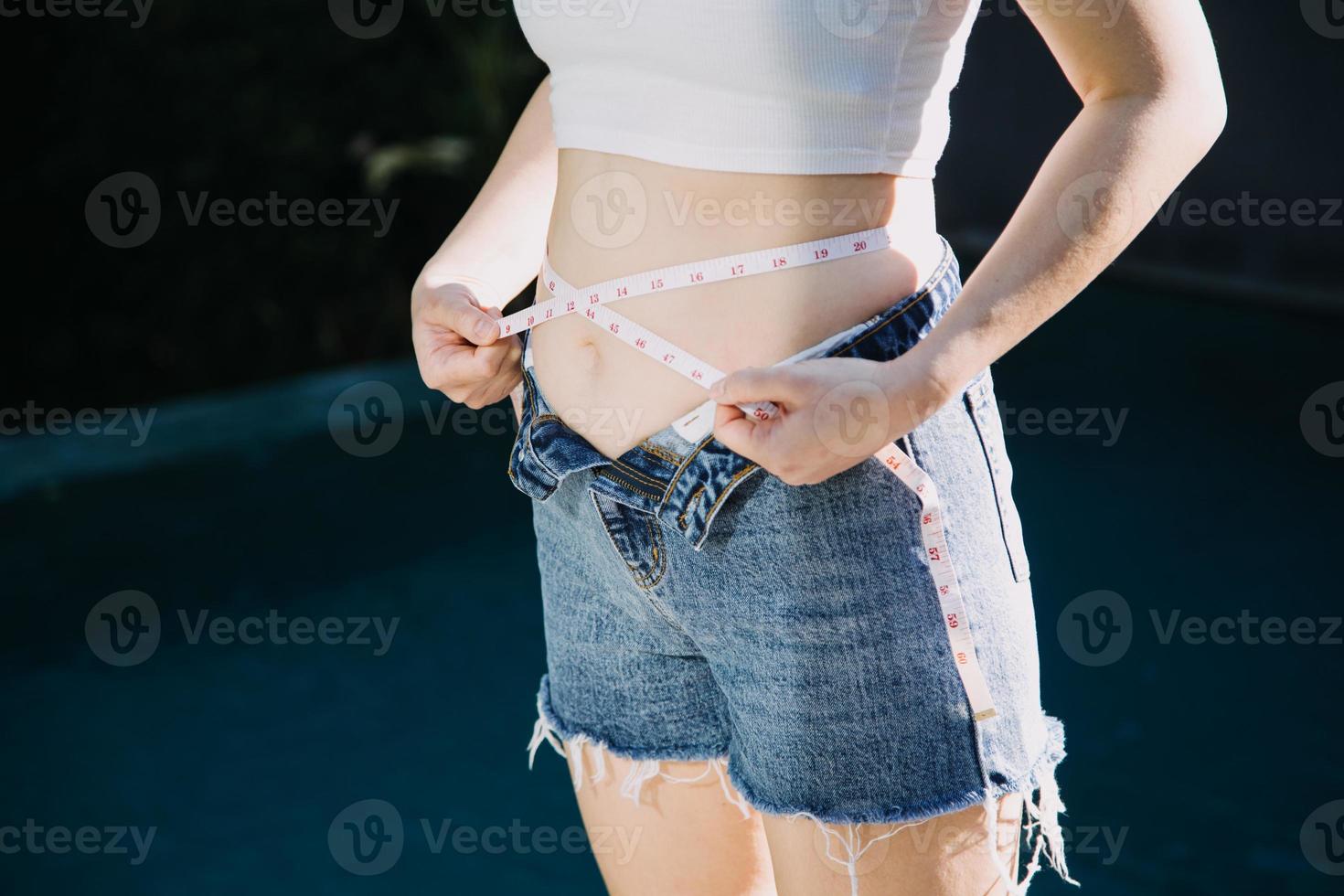 mujer gorda, barriga gorda, gordita, mujer obesa mano sosteniendo grasa abdominal excesiva con cinta métrica, concepto de estilo de vida de dieta de mujer foto