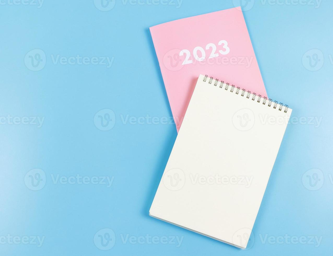 flat lay of blank paper note book on pink diary 2023 on blue  background. photo