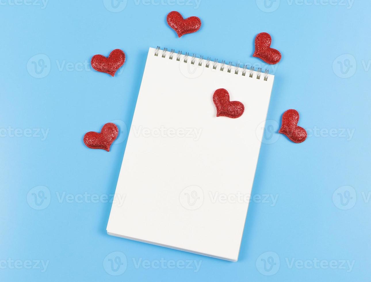 flat lay of opened  notebook with red glitter hearts on blue  background with copy space. Love, Valentine's day, memory. photo