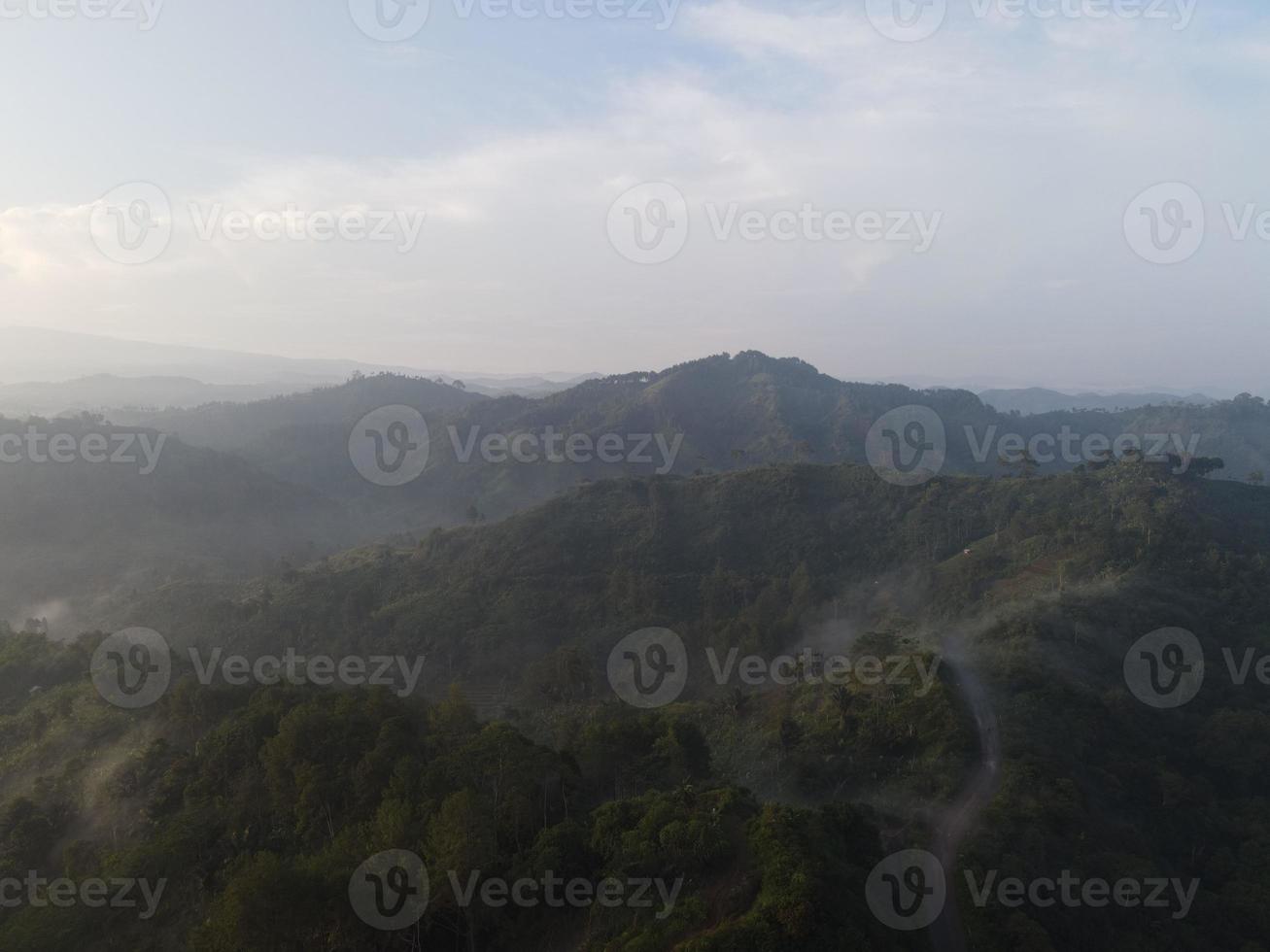 Aerial view of foggy forest landscape in Indonesia at sunrise. photo