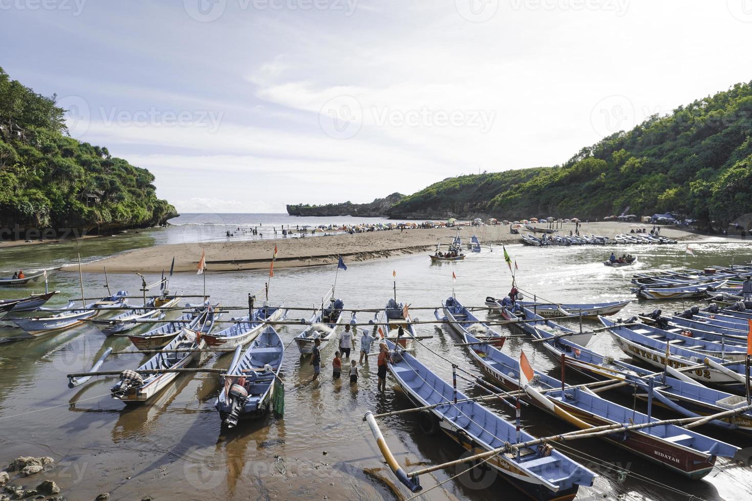 Baron Beach in Gunung Kidul, Indonesia with visitor and traditional boat. Yogyakarta, Indonesia - January, 2023. photo