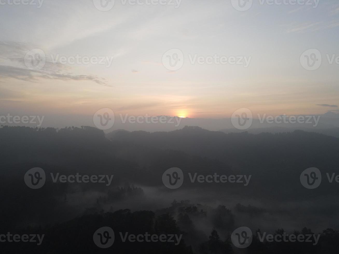 Aerial view of foggy forest landscape in Indonesia at sunrise. photo