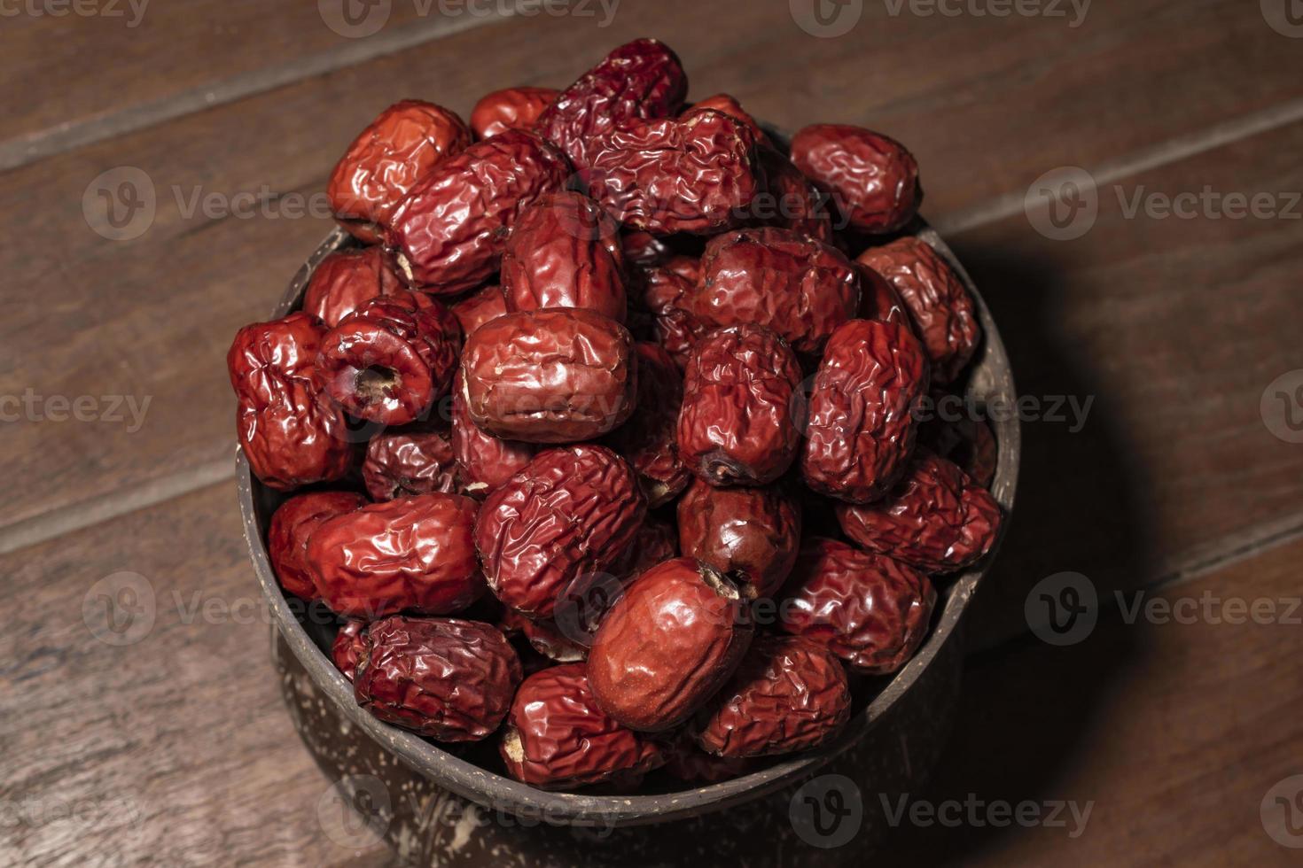 Dry jujube or chinese date in coconut bowl on wood background. photo