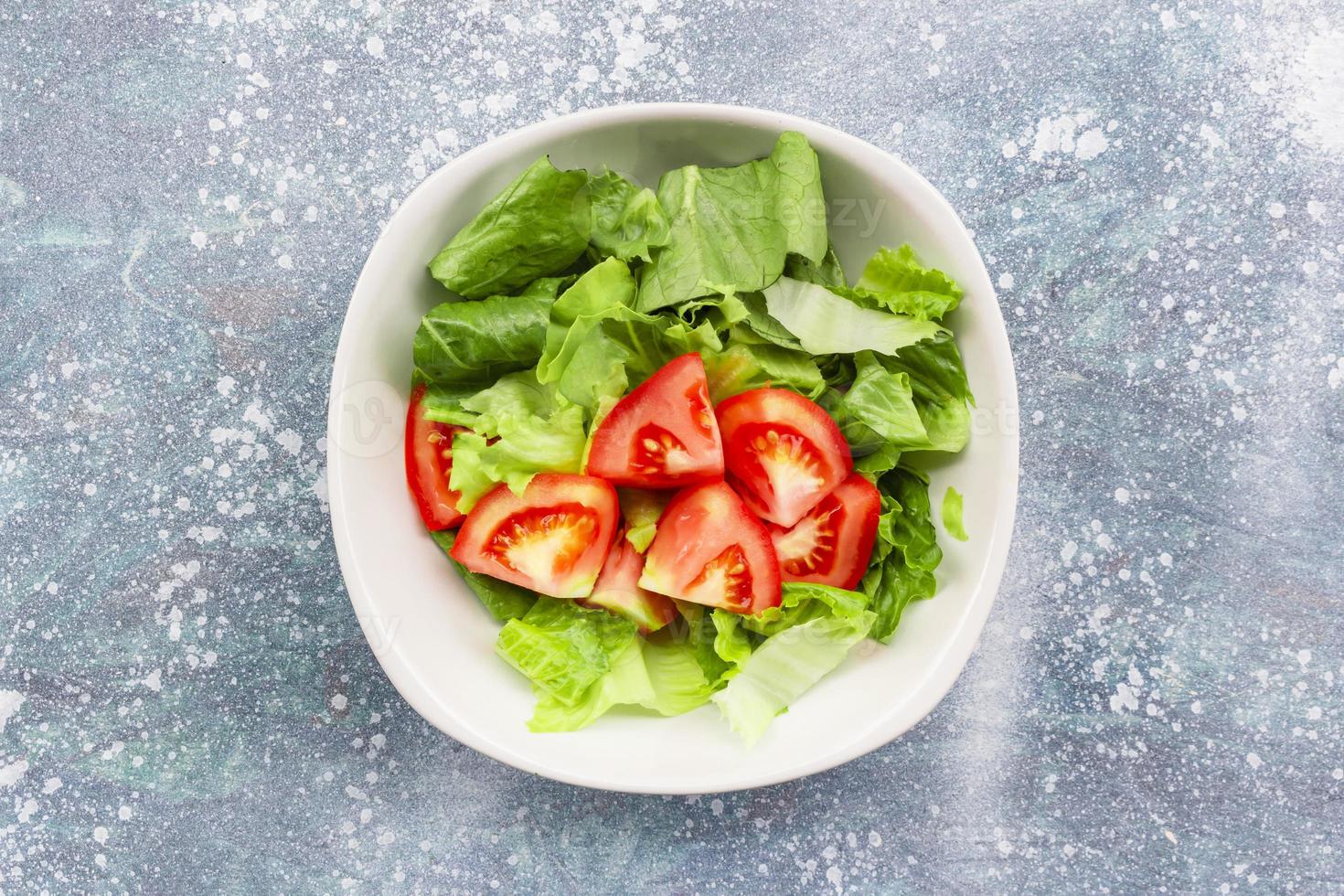 Healthy food tomato vegetable salad in bowl on blue wood background. photo