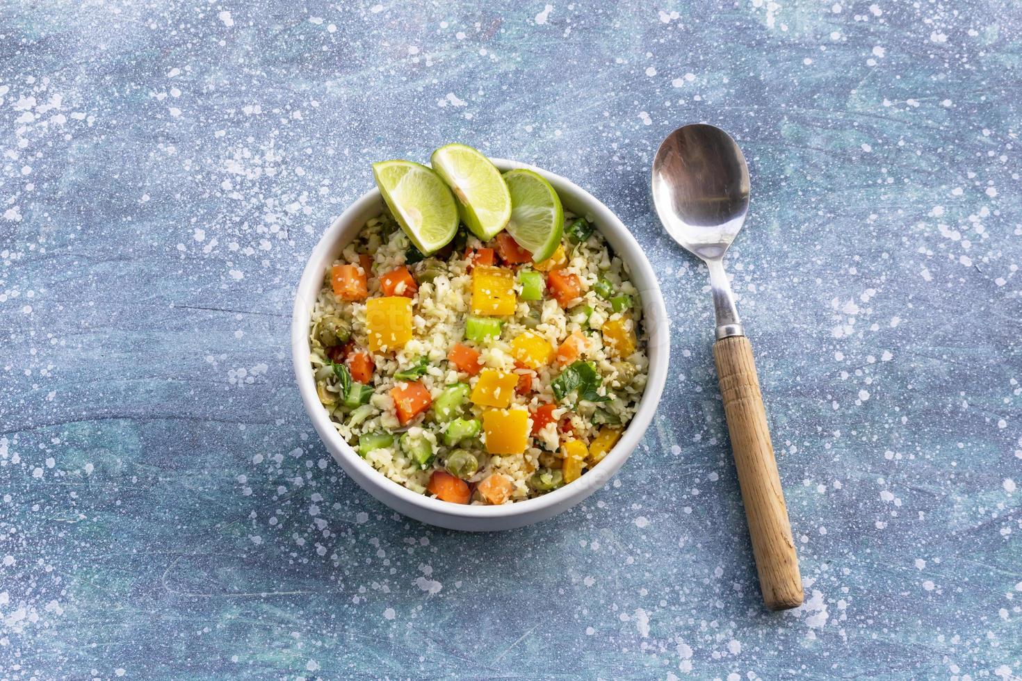 Healthy food cauliflower fried rice has vegetable in white bowl on blue wood table. photo