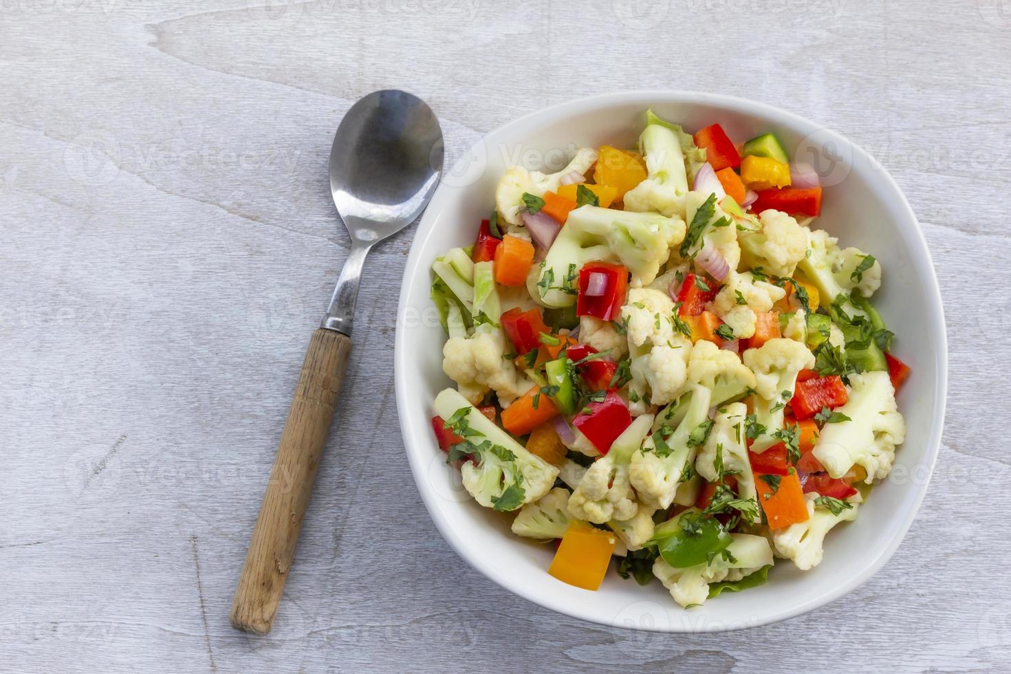 Healthy cauliflower salad in white bowl on wood background. photo