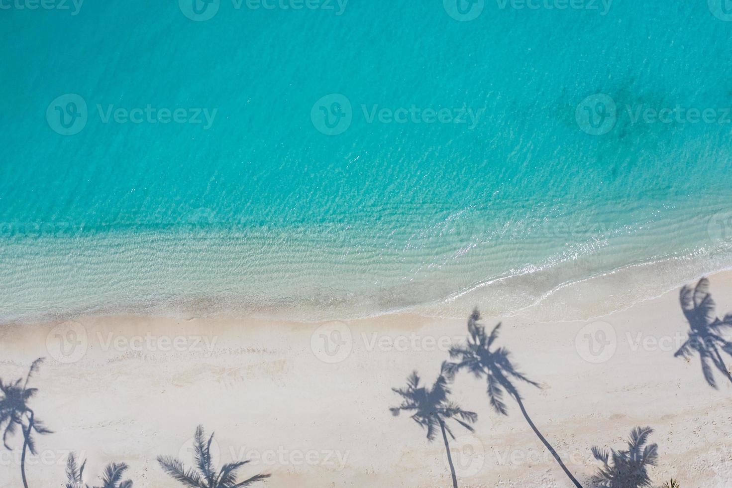 paisaje de playa aérea. Vista de la playa minimalista desde un avión no tripulado o un avión, sombras de palmeras en la arena blanca cerca del mar azul con hermosas ondulaciones y olas. banner de paisaje de playa de verano perfecto. exótico mar azul foto